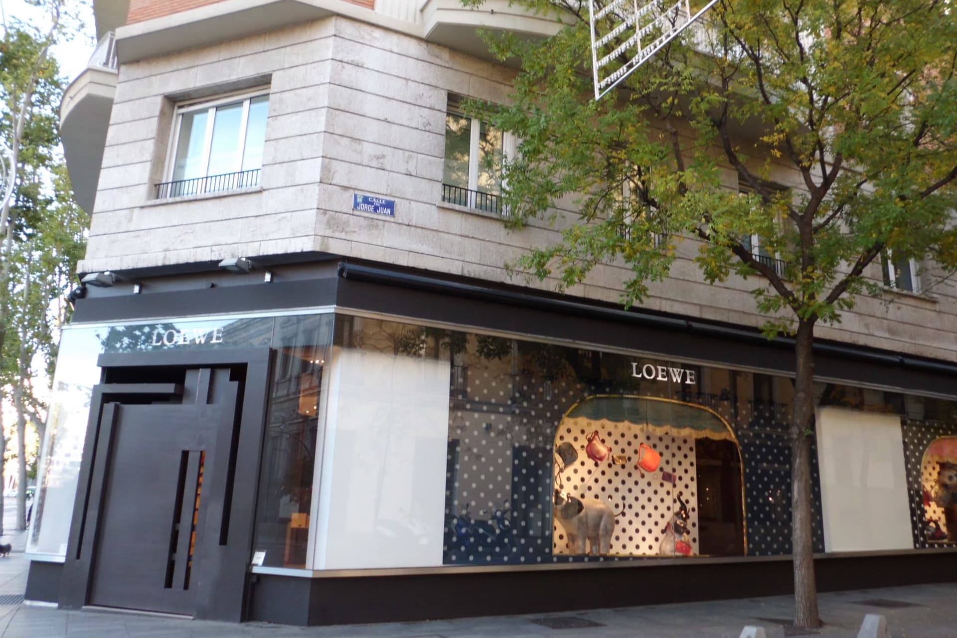 A quiet shopping street in Madrid's Salamanca district, with awnings and small boutique fronts.