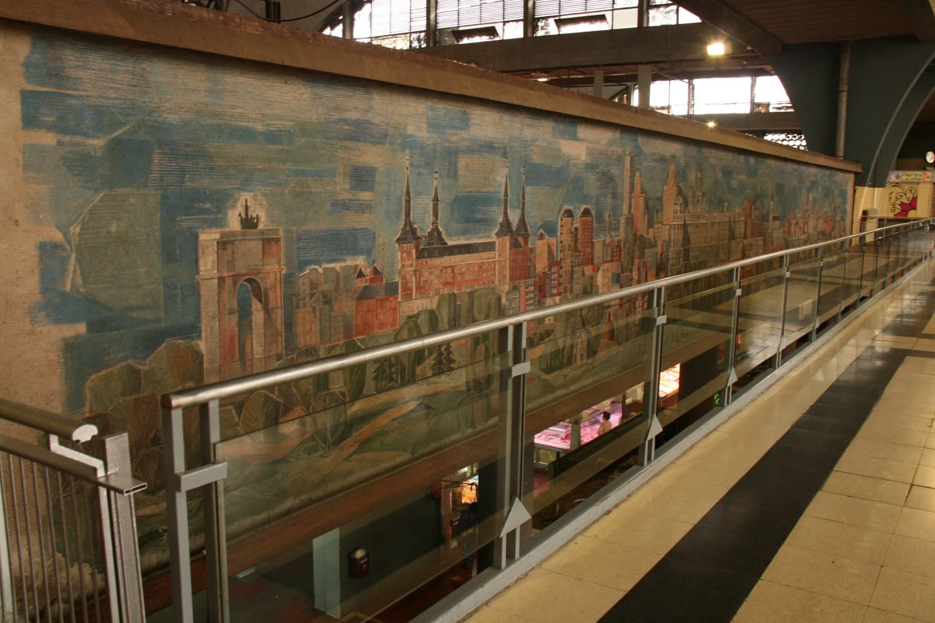 Inside Mercado de la Cebada in Madrid, produce stalls under the market hall's steel roof.