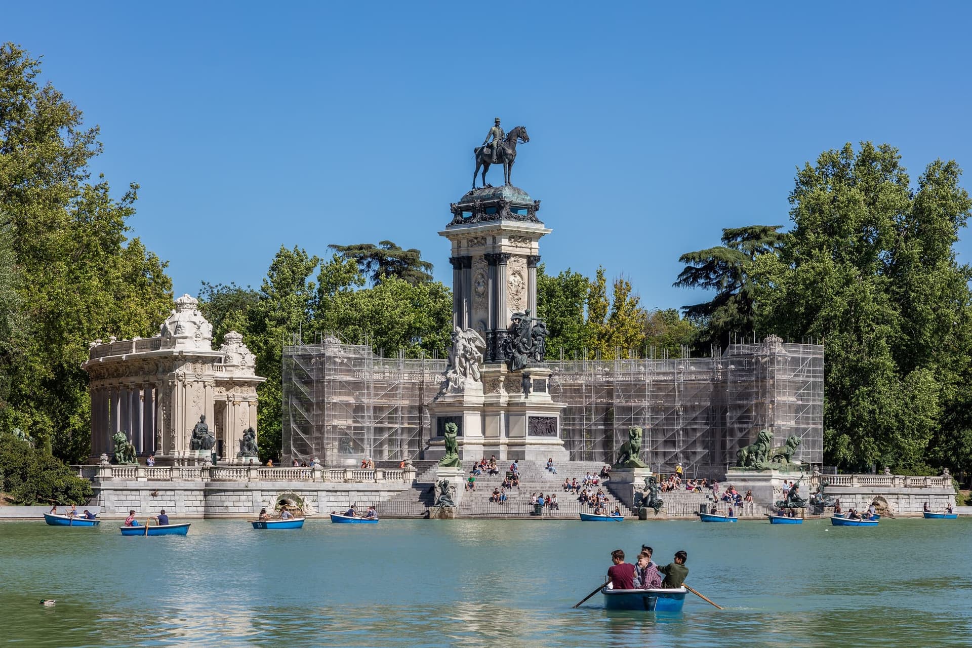The boating lake in Madrid's Retiro park, with rowing boats on the water and a colonnade behind it.