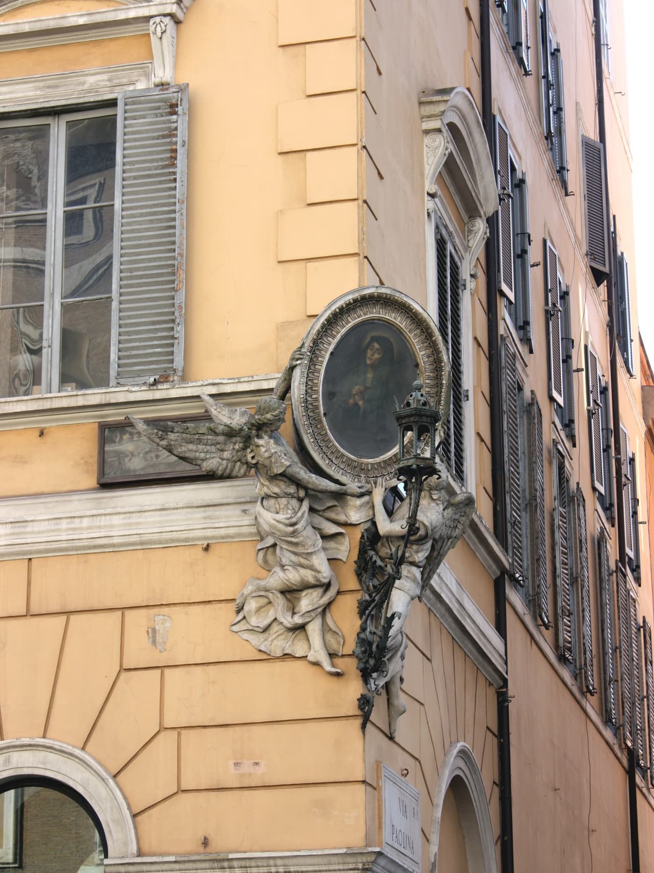 A painted corner shrine and weathered stucco on a building in the Monti district of Rome.