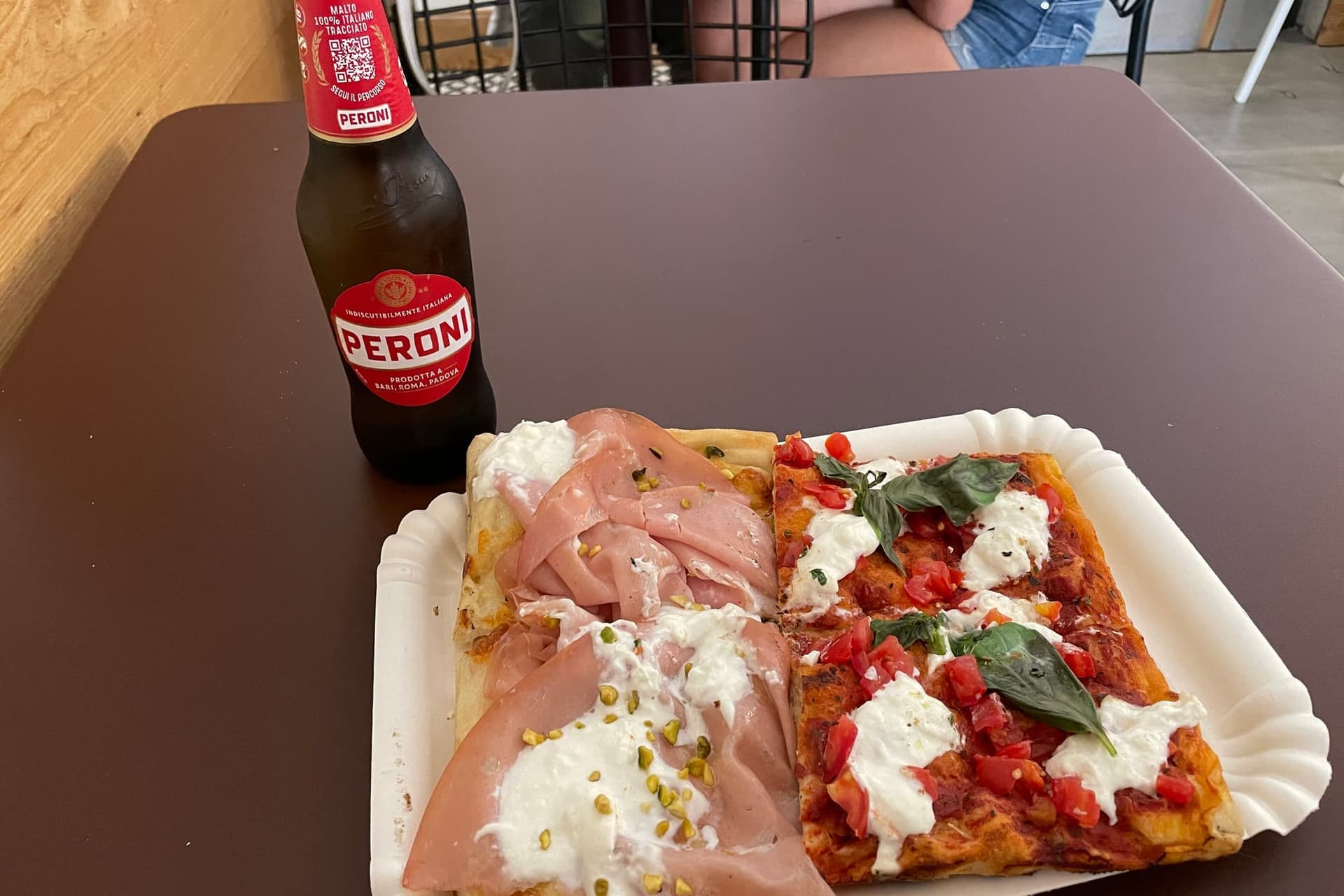 Rectangular trays of Roman pizza al taglio behind glass, cut into slices and sold by weight.